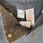 Close-up of the waistband and inner pocket area of a pair of Nike jeans, showing a faded gray denim fabric, interior labels, and a hangtag.